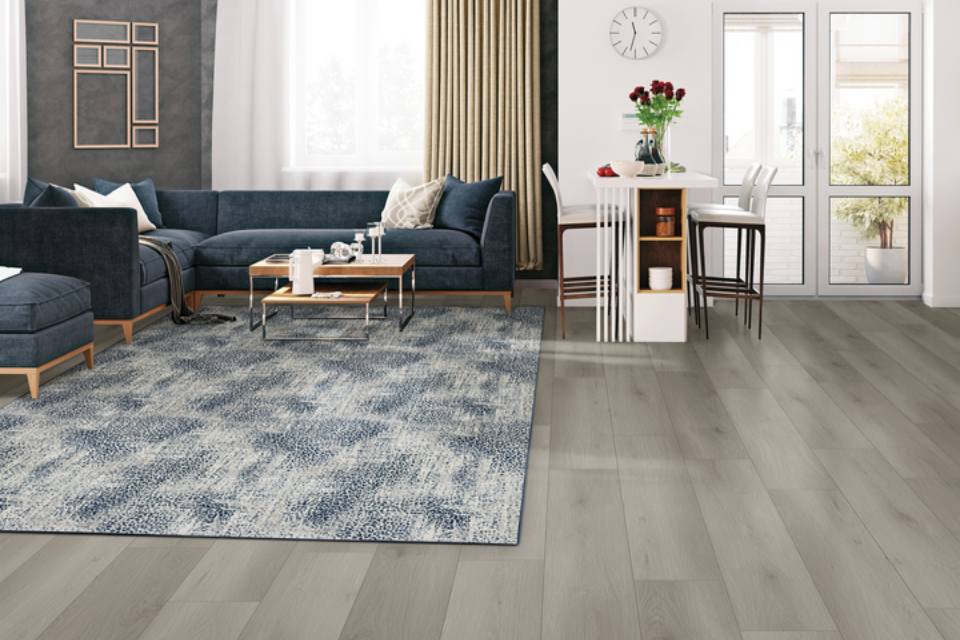 blue patterned area rug in living room with blue couch and grey wood look flooring